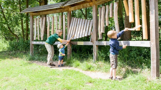 Försterin zeigt Kindern Holzinstromente im Wald und stärkt Forstgemeinschaft