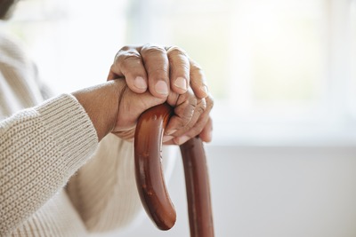 Alte Person umklammert einen Gehstock