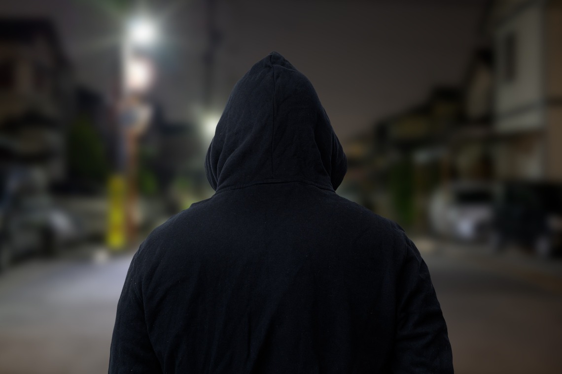 Ein Mann im dunklen Kaputzenpulli in der Nacht