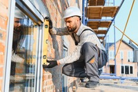 Ein Handwerker, der ein Fenster montiert. Das Bild zeigt einen Handwerker, der ein Fenster montiert.