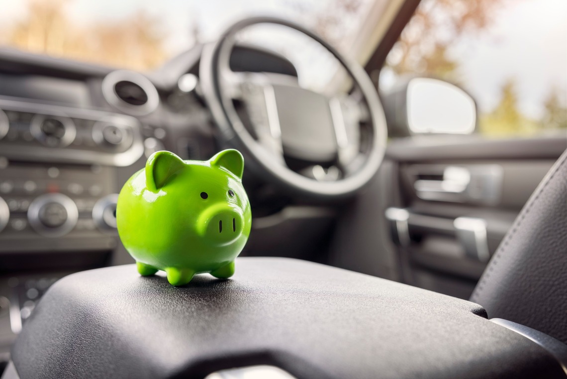 Ein Spaarschwein steht auf der Mittelkonsole im inneren des Autos