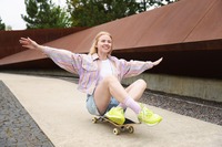 Das Bild zeigt eine Frau, die auf einem Skateboard fährt. 