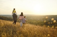 Familie mit zwei Kindern läuft auf Wiese entlang