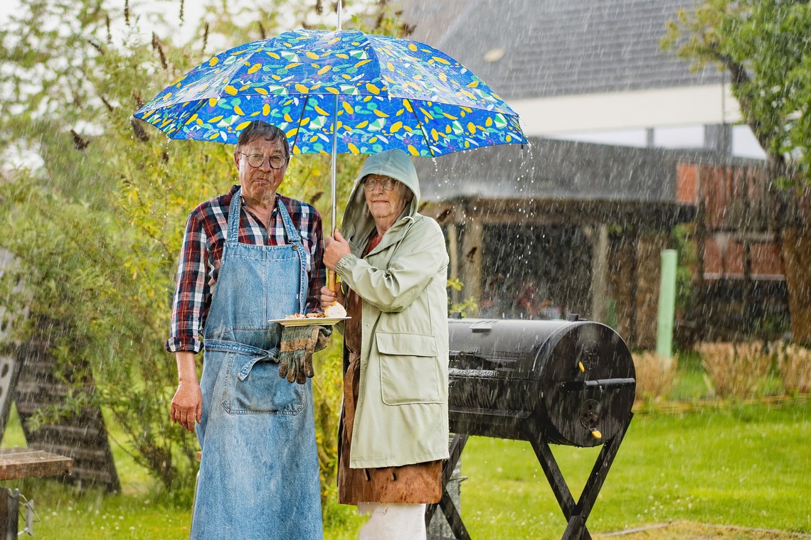 Eine Familie im Regen vor einem Grill